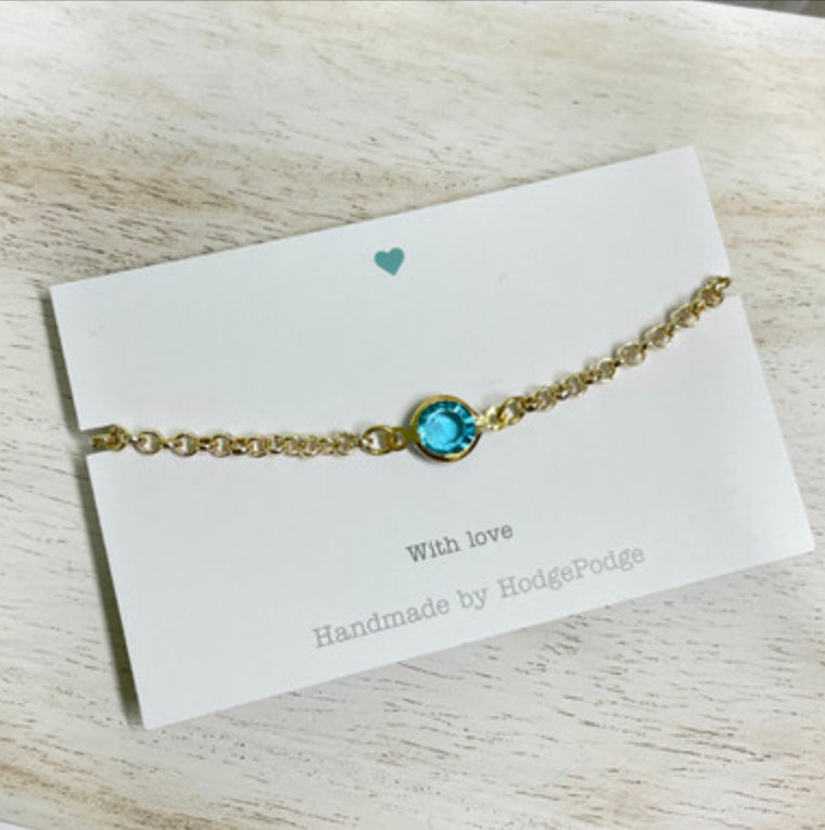 Gold belcher chain bracelet with blue glass link charm