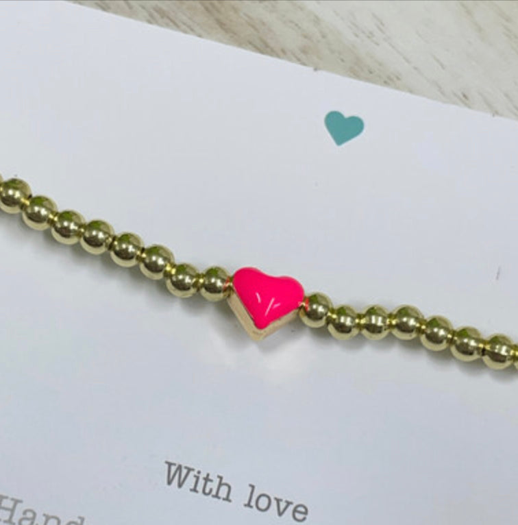 Gold bead bracelet with bright pink heart