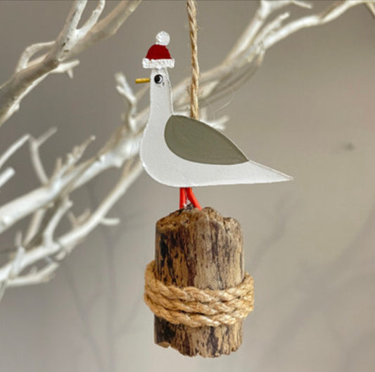 Seagull in bobble hat on groyne hanging Christmas decoration by Shoeless Joe