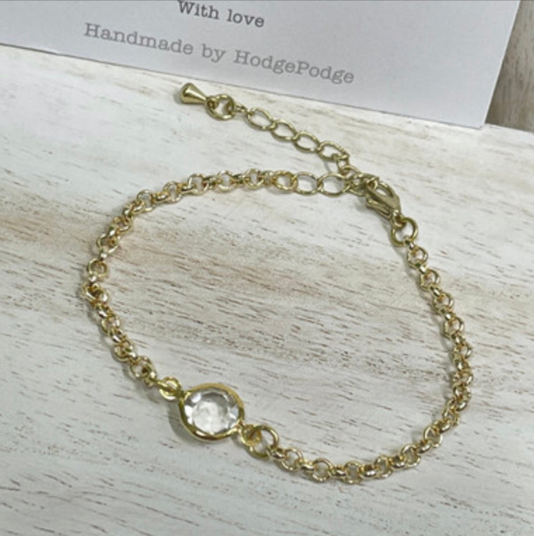 Gold belcher chain bracelet with clear stone link.