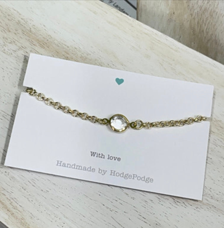 Gold belcher chain bracelet with clear stone link.