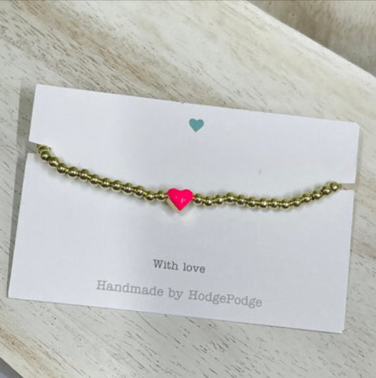 Gold bead bracelet with bright pink heart