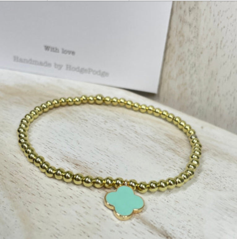Gold bead bracelet with an enamel clover charm