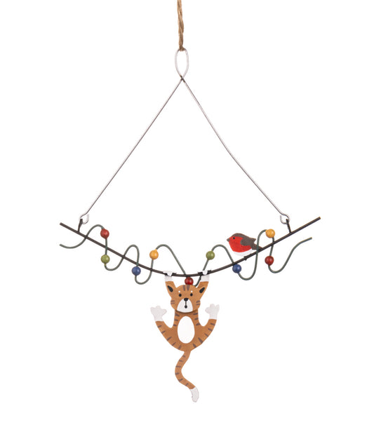 Cat hanging to Christmas lights. Tree decoration