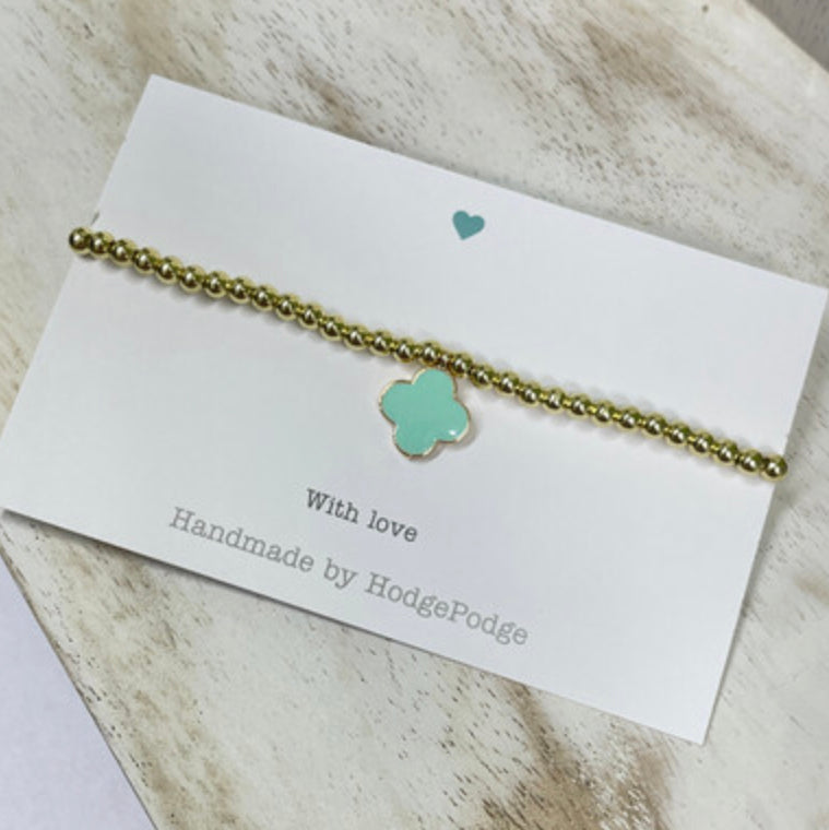 Gold bead bracelet with an enamel clover charm